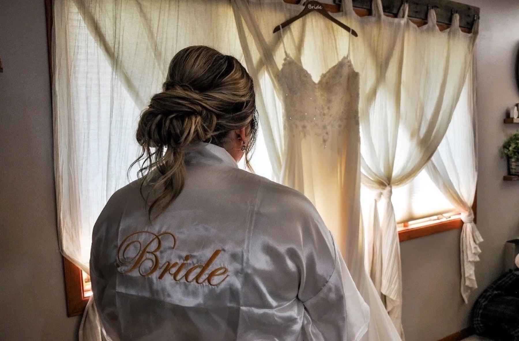 Bride in her robe beside her gown on the morning of the wedding